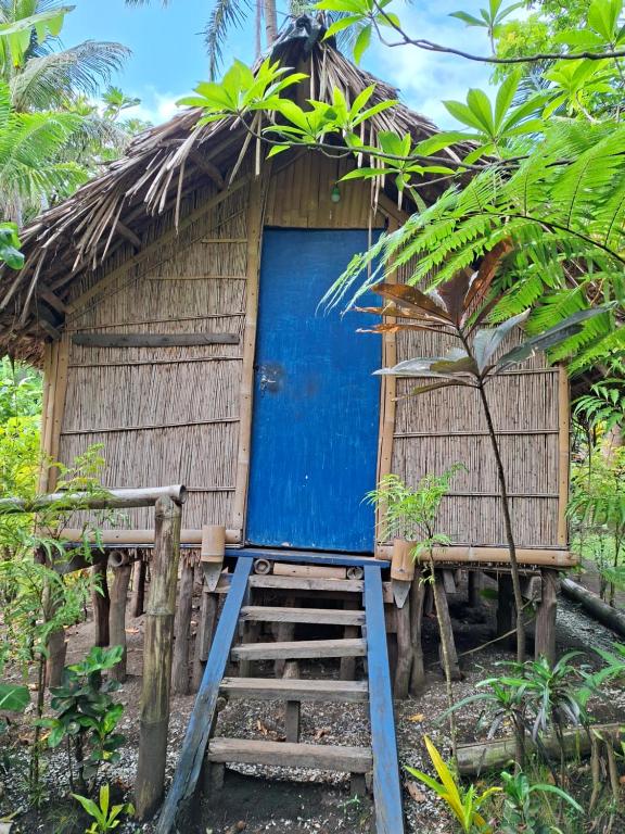 a small hut with a blue door in a forest at Ash and Ocean BUNGALOW in Loméméti