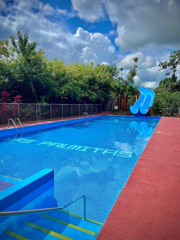 a swimming pool with a slide in the middle at Centro Turístico Las Palmitas in Muelle del Arenal