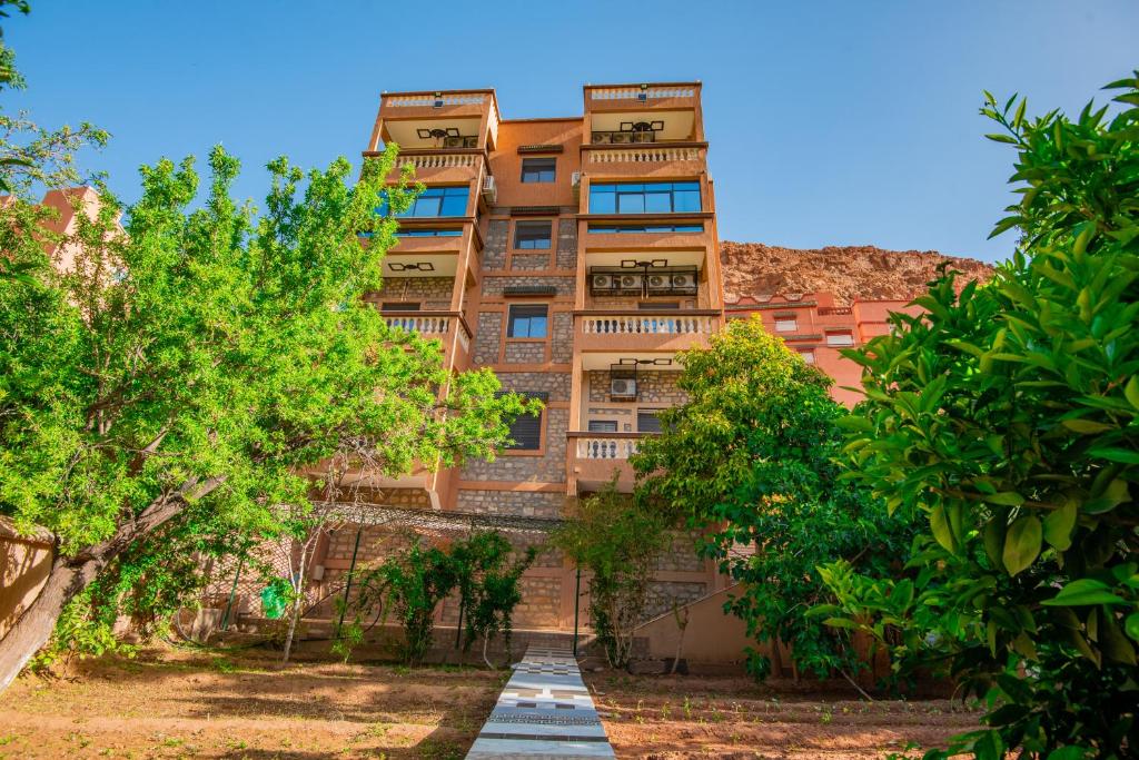 a tall brick building with trees in front of it at Relais Des Nomades in Tinerhir