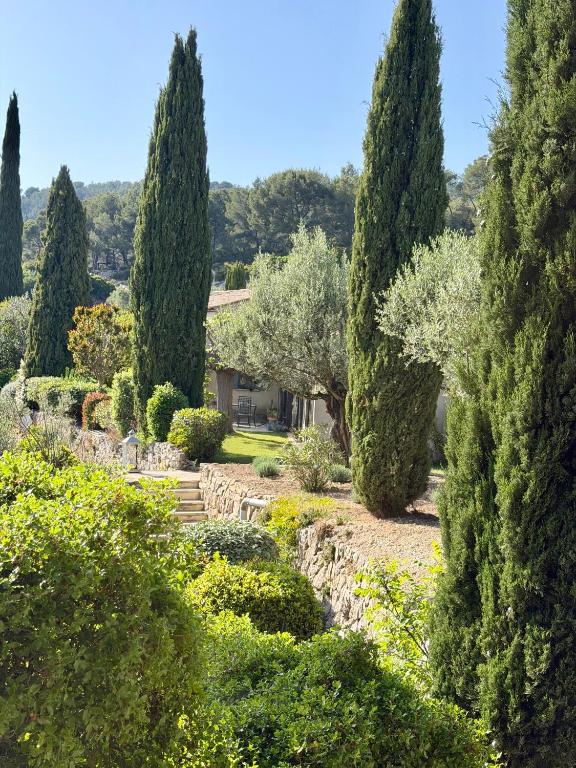 a garden with trees and bushes and a house at Chambres et tables d'hôtes , spa et séjour bien être , Le Clos de la Chèvre Sud in La Cadière-dʼAzur