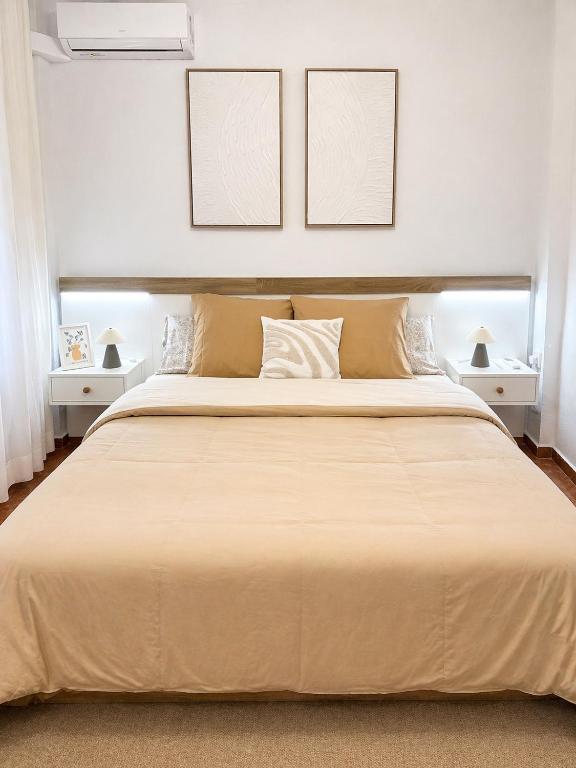 a bedroom with a large bed with two pictures on the wall at Apartamento Laurencia in Fuente Obejuna