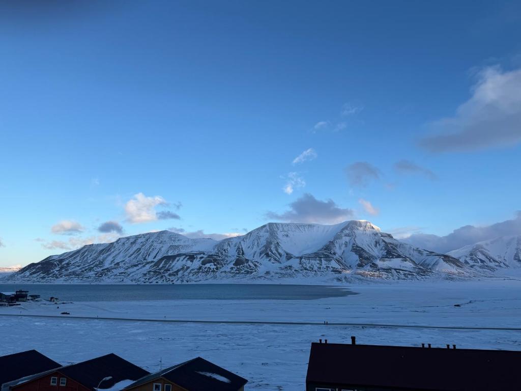 a view of snow covered mountains and a body of water at Koselig rekkehus i Longyearbyen in Longyearbyen