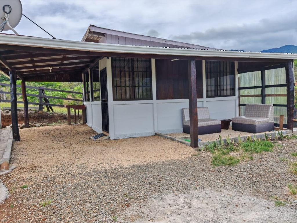 a house with two chairs and a roof at Hospedaje La Guaca in Bagaces