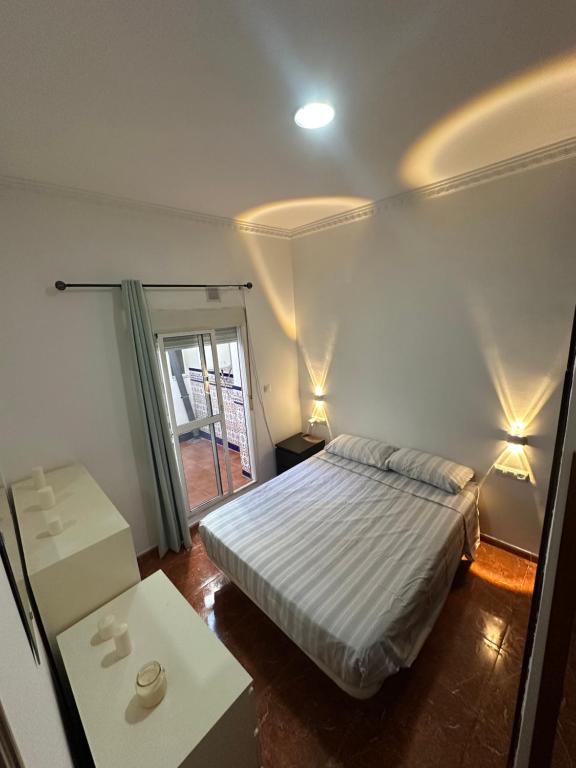 a bedroom with a bed and a table and a window at Apartamento La Línea 1 in La Línea de la Concepción