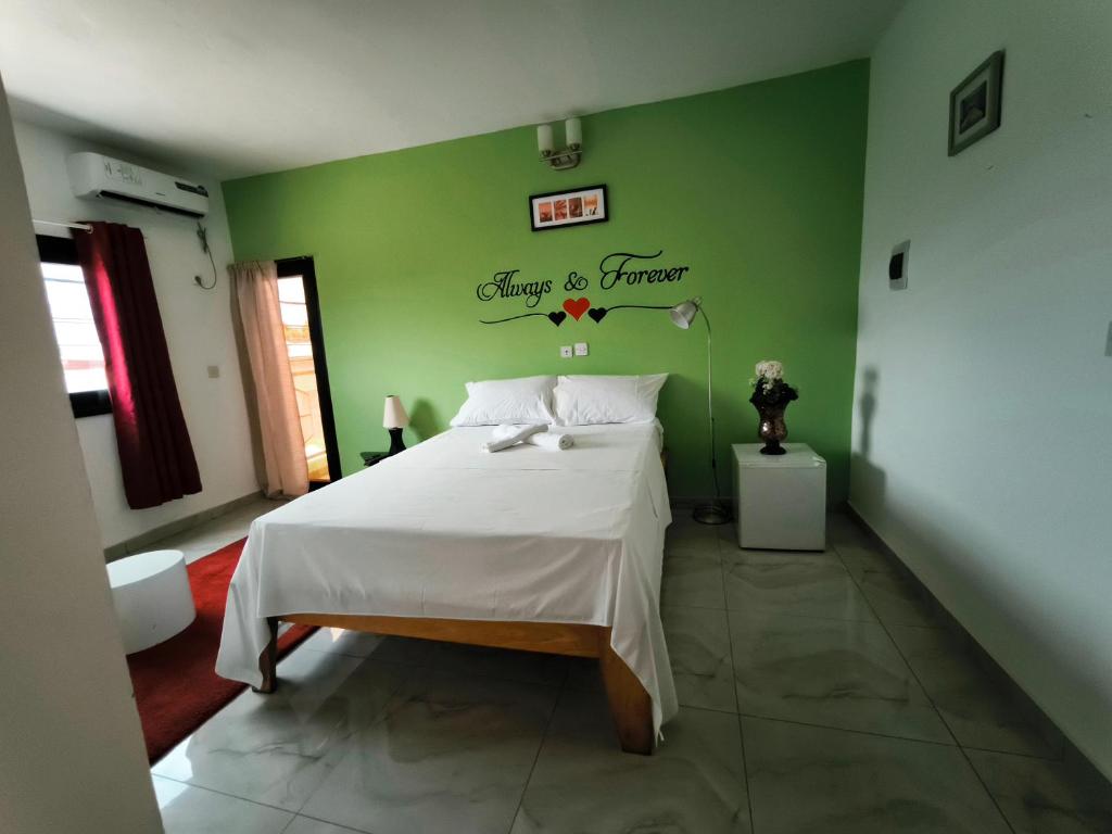 a bedroom with a white bed and a green wall at O'soho GarDens BingerVille in Bingerville