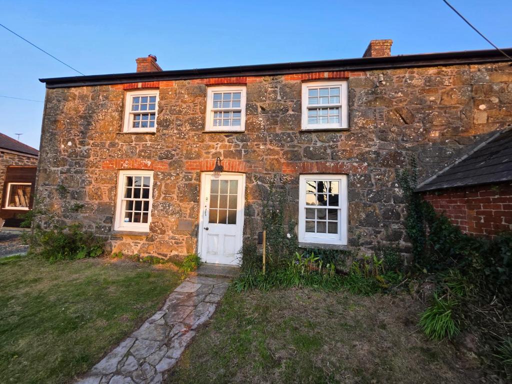 an old stone house with white doors and windows at Postmasters House in Helston