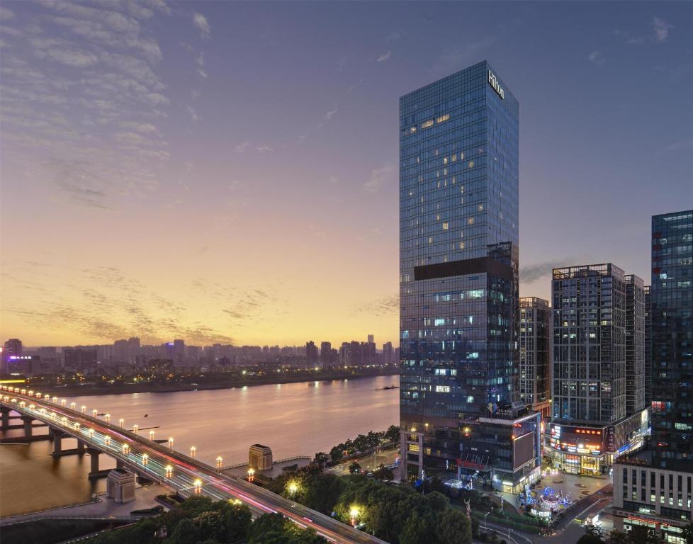 a city skyline with a river and a tall building at Hilton Zhuzhou in Zhuzhou