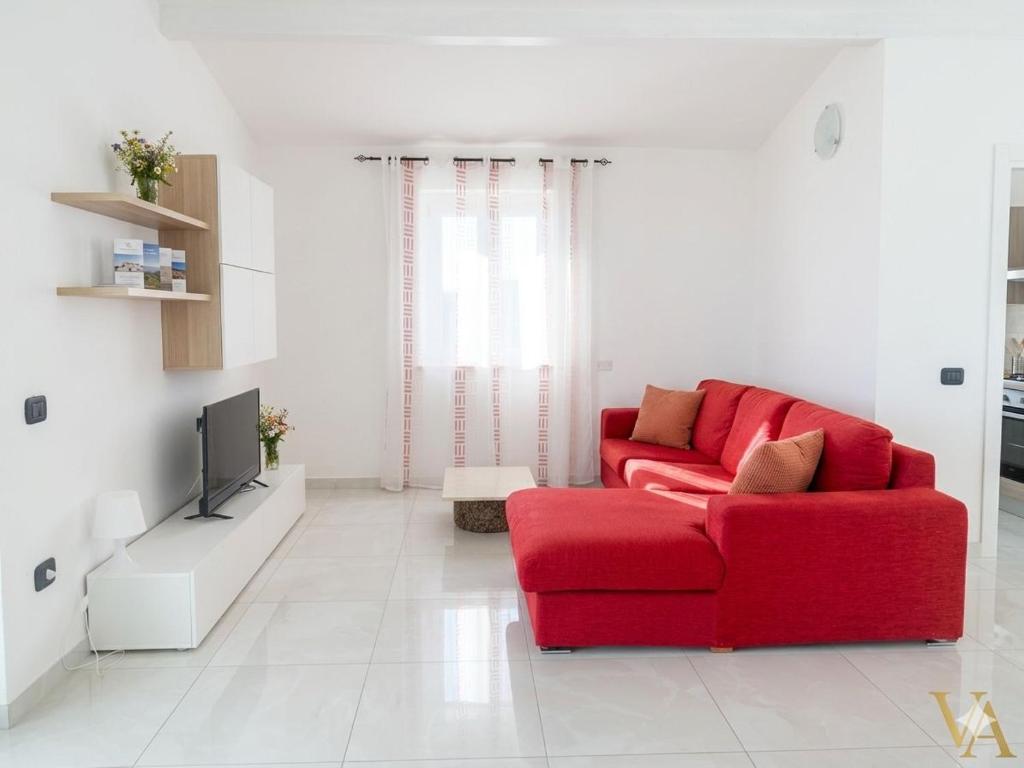 a living room with a red couch and a tv at VILLA ARCANGELO Le in Mandatoriccio Marina