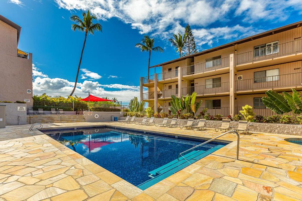 a swimming pool in front of a building at Kihei Alii Kai Ocean View Condo Pool, Hot Tub, Sauna, AC, Sleeps 4 in Kihei
