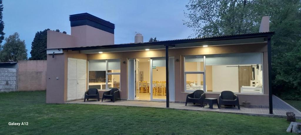 a house with glass doors and chairs in a yard at QUINTA CERRO LARGO Olavarria in Olavarría