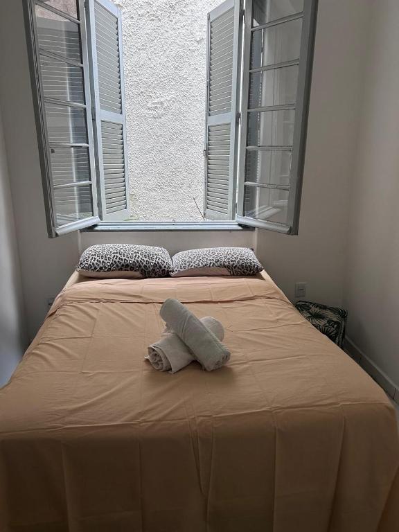 a towel sitting on top of a bed with a window at Hostel Bahia POA Próx Shopping Total, Rodoviária e Hospital Presidente Vargas in Porto Alegre