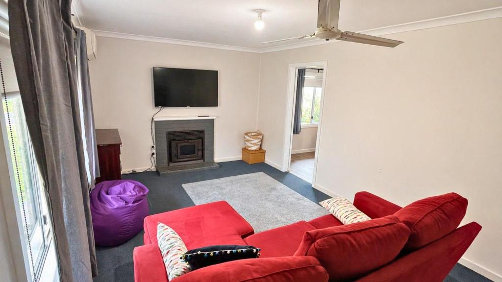 a living room with a red couch and a fireplace at Family Beachside Shack in Geographe