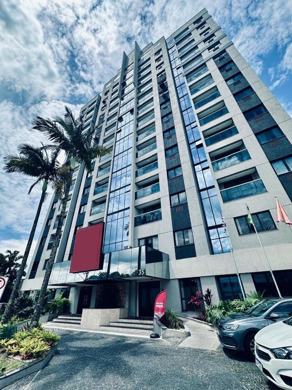 a large building with palm trees in front of it at BLUE HAT - Apart Hotel in Mogi das Cruzes