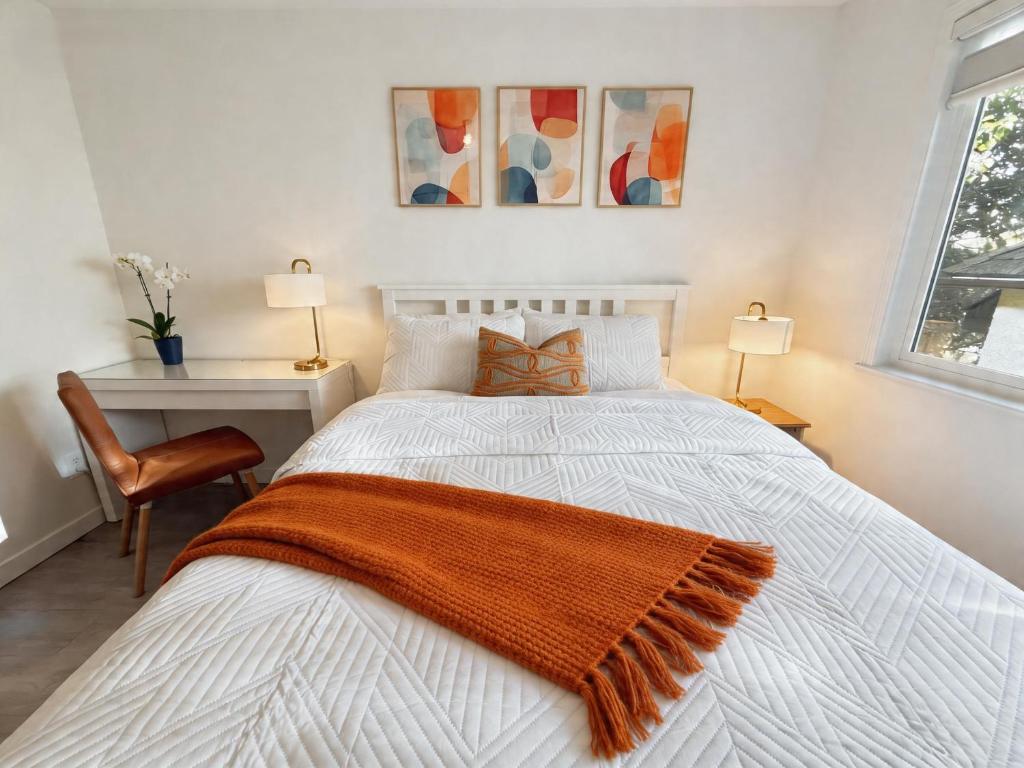 a bedroom with a white bed with an orange blanket on it at Vancouver Lucy House in Vancouver