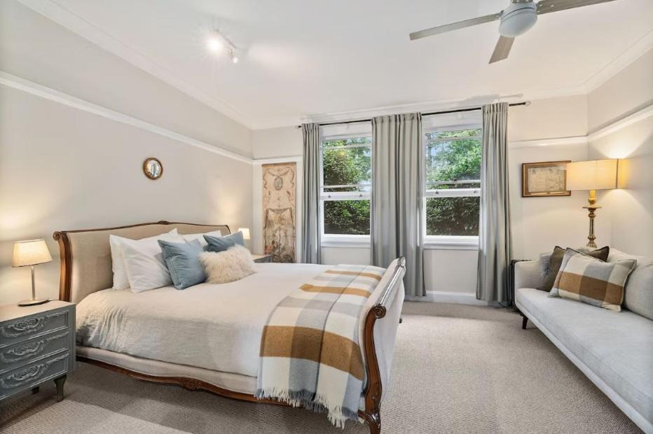 a white bedroom with a bed and a couch at Centennial Cottage 1 - 'Boorool' in Bowral