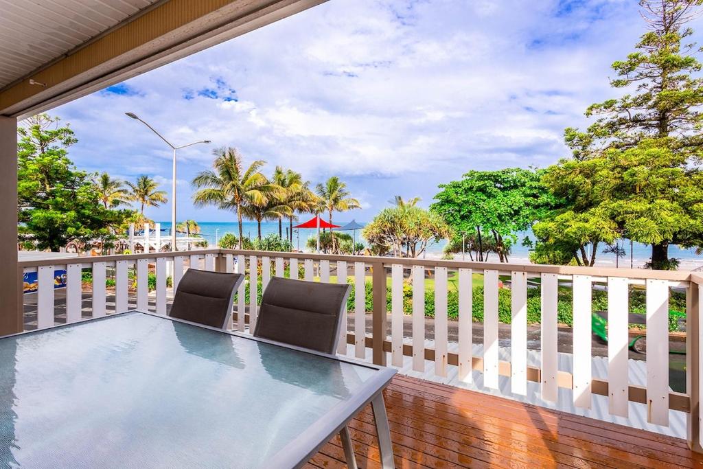 a balcony with a table and chairs and the beach at Sunrise on the Esplanade in Yeppoon