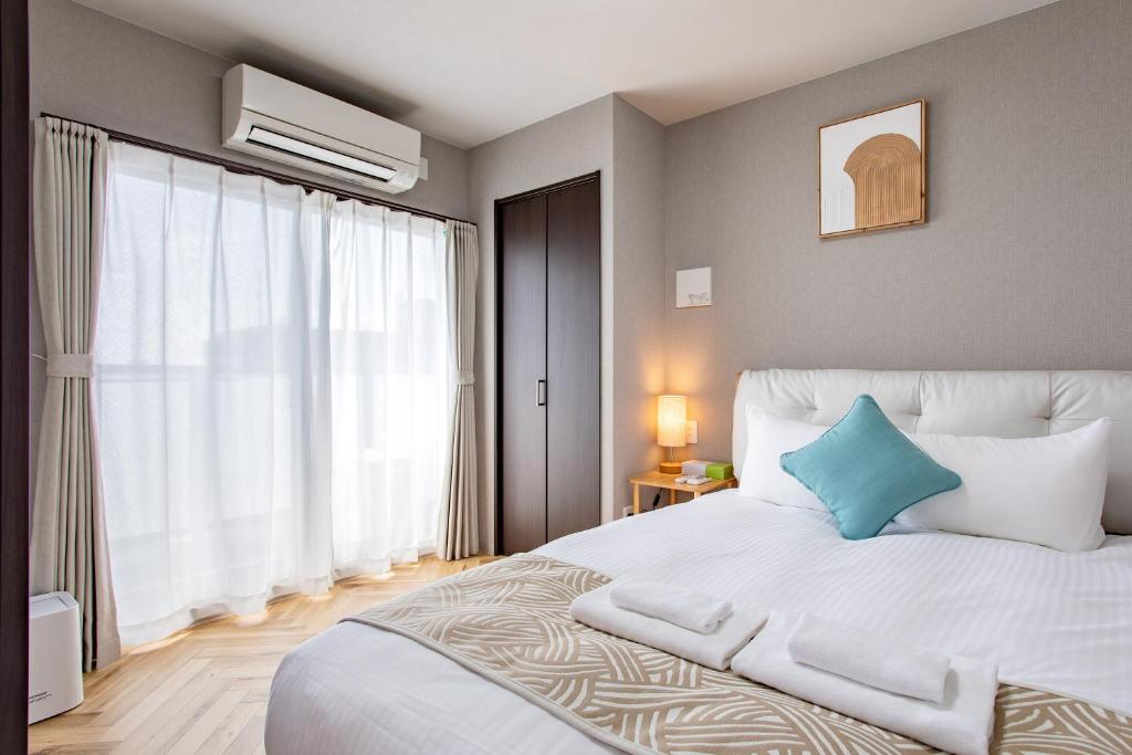 a bedroom with a white bed with a blue pillow at Hopetree NambaImamiya in Osaka