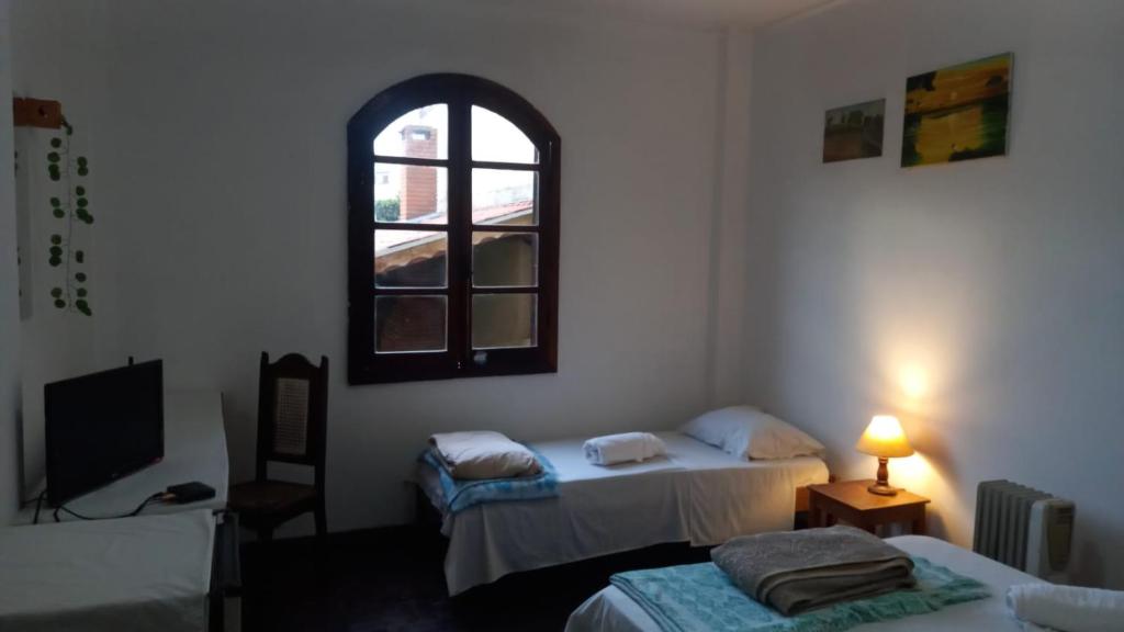 a room with two beds and a window at Pousada Vila Bela in Poços de Caldas