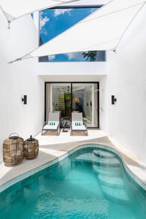 a swimming pool with two chairs and a house at The Arc House Canggu in Canggu