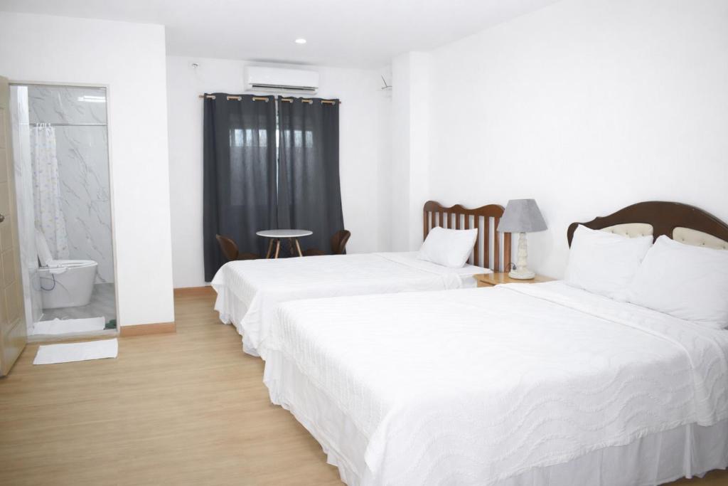 two beds in a room with white walls and wood floors at Koa Guest House in Angeles