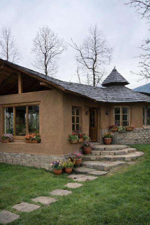 a house with potted plants in front of it at Sarayu Farmstays in Manāli