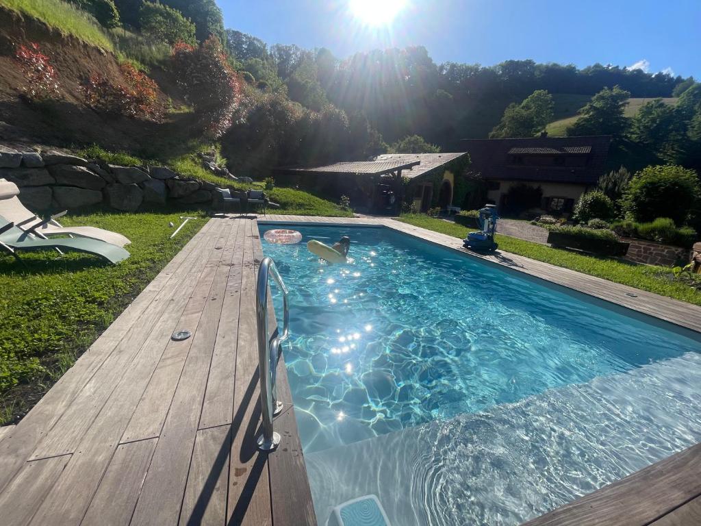 a swimming pool on a wooden deck with the sun in the background at Gite Marie Rose in Sainte-Marie-aux-Mines