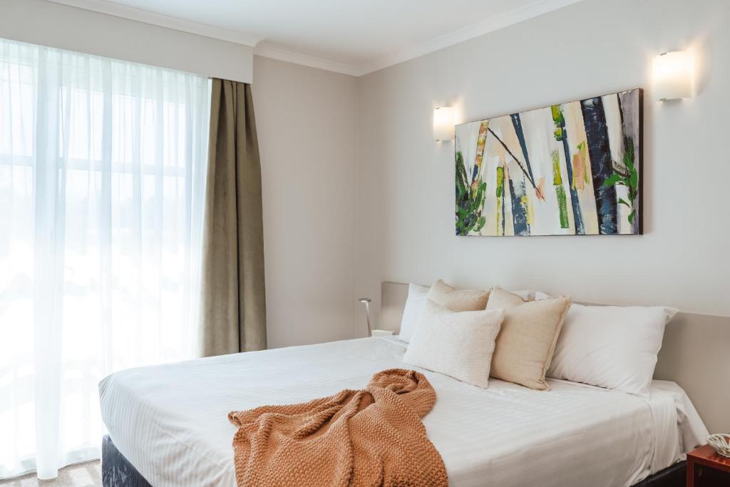 a bedroom with a white bed with a blanket on it at Punthill Narrabundah in Canberra