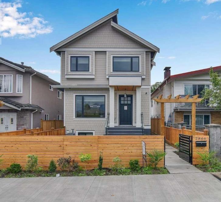 a house with a wooden fence in front of it at Private Bachelor Suite Near PNE in Vancouver