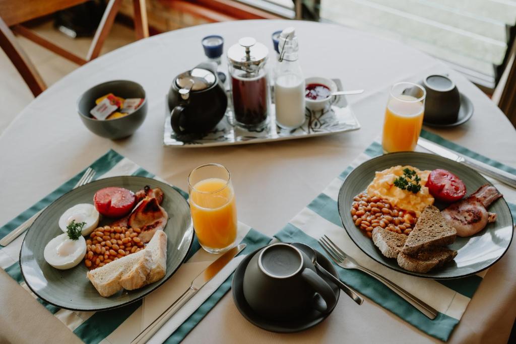 a table with two plates of breakfast foods and orange juice at Riverside Rest Nambucca Heads in Nambucca Heads