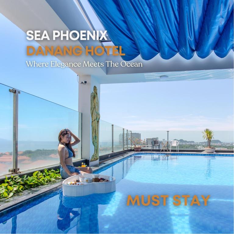 a woman sitting on the edge of a swimming pool at Sea Phoenix Hotel Da Nang in Danang