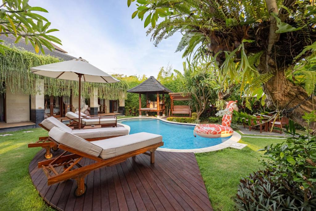 a backyard with a pool with a chair and an umbrella at Cove Ayuna in Canggu