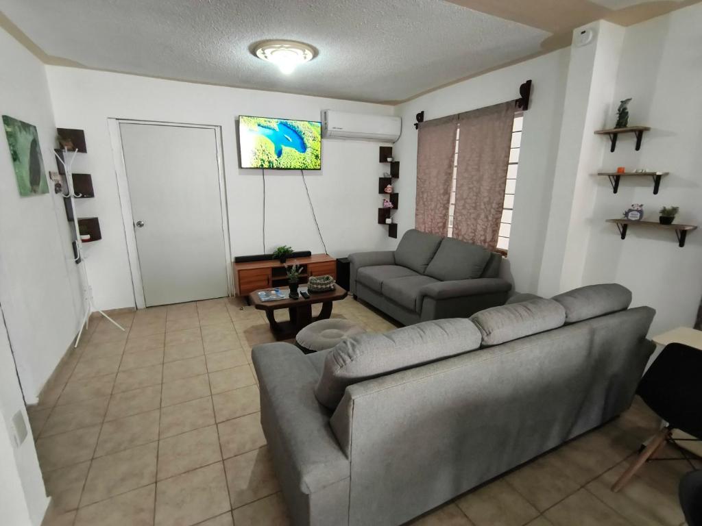 ein Wohnzimmer mit Sofa und Fernseher in der Unterkunft SweetHome con amplio y fresco patio in Tampico