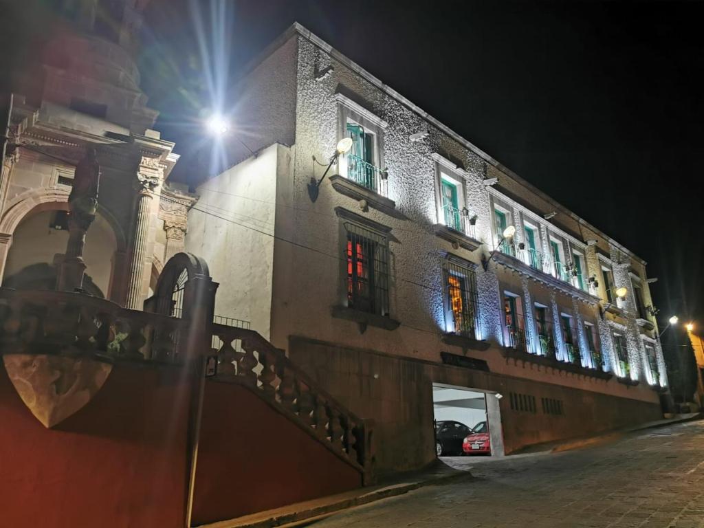 a building with lit windows on a street at night at hotel la ermita suites in San Miguel de Allende