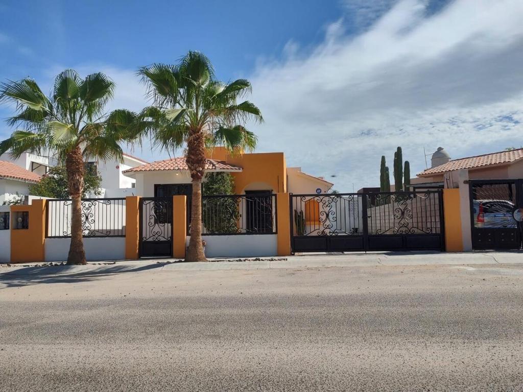 a house with palm trees in front of a fence at Casa Mojave in La Paz