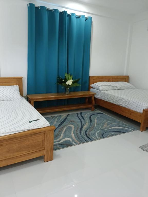 a room with three beds and a blue curtain at The Avenue Hotel and Event Center in Manaoag