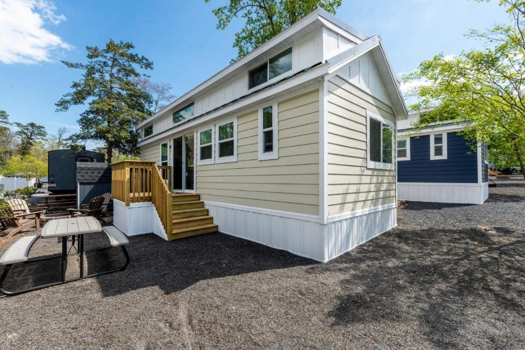 a white tiny house with a porch and stairs at 2 Homes • Pool + Amenities • Sleeps 16 in Swain