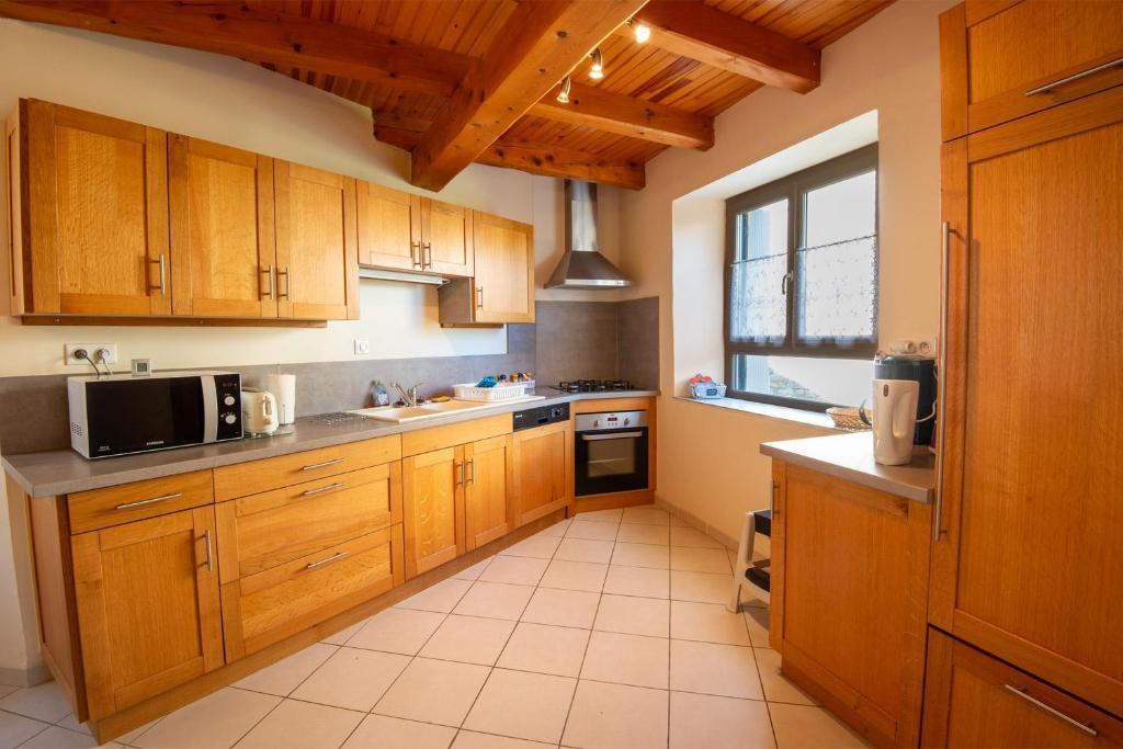 a kitchen with wooden cabinets and a sink and a microwave at L'oustal de lucie in Saint-Saturnin-de-Tartaronne