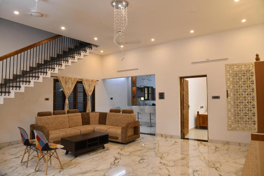 a living room with a couch and a staircase at Aadhya Abode Holiday Home in Kanyakumari