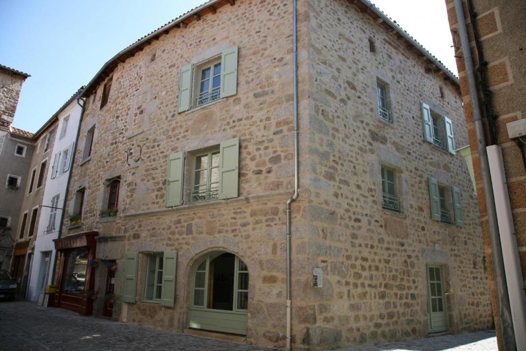 an old brick building with a door in a street at Maison pierre de mercoeur in Le Malzieu-Ville