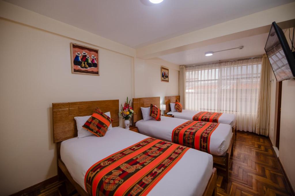 a room with two beds and a window at Quechua Hostal Recoleta in Cusco