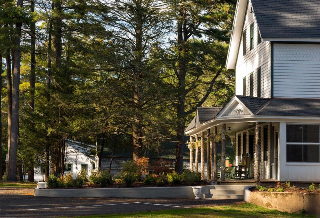 a white house with a porch and trees at Pine Brook Manor in Sparrow Bush