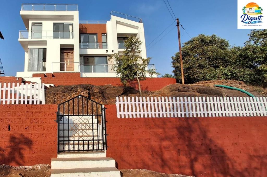 a building behind a red wall with a gate at Digant Home Retreat in Nevra