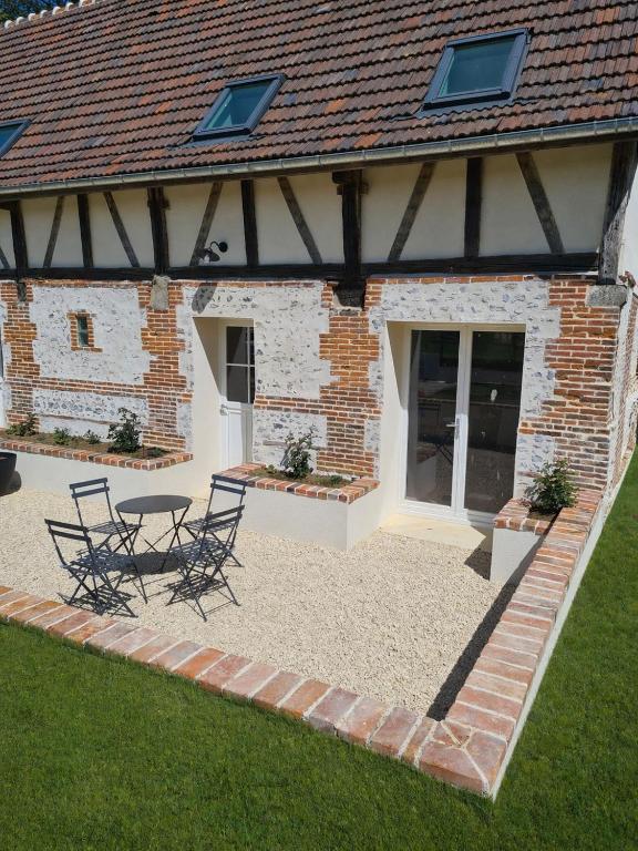 a patio with chairs and a table in front of a building at Au pré de Mimi in Lalande-en-Son