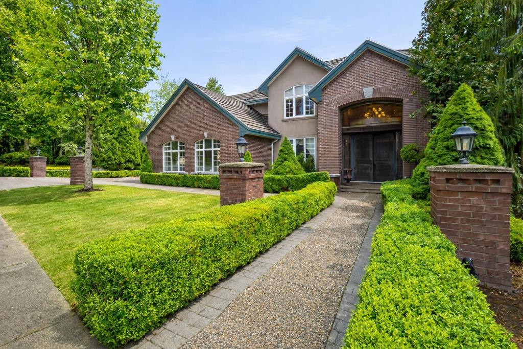 a brick house with a green hedge at Hampton Luxe House in Coquitlam