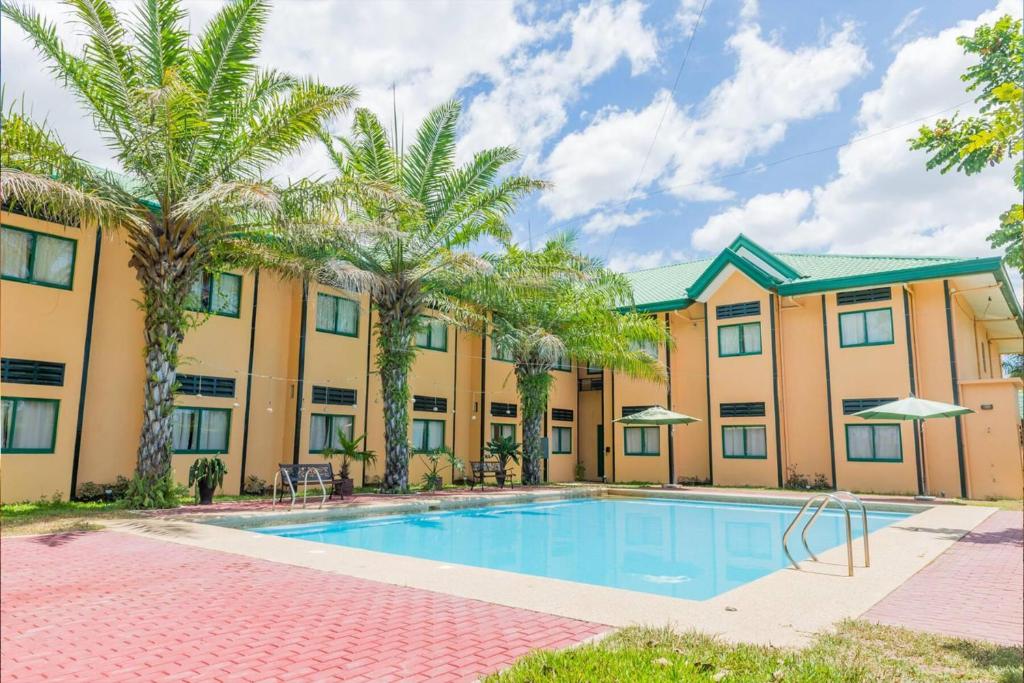 a pool in front of a building with palm trees at Microtel by Wyndham Cabanatuan in Cabanatuan