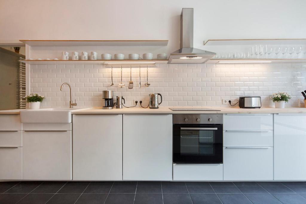 ベルリンにあるModern Design Apartmentの白いキャビネットとシンク付きのキッチン