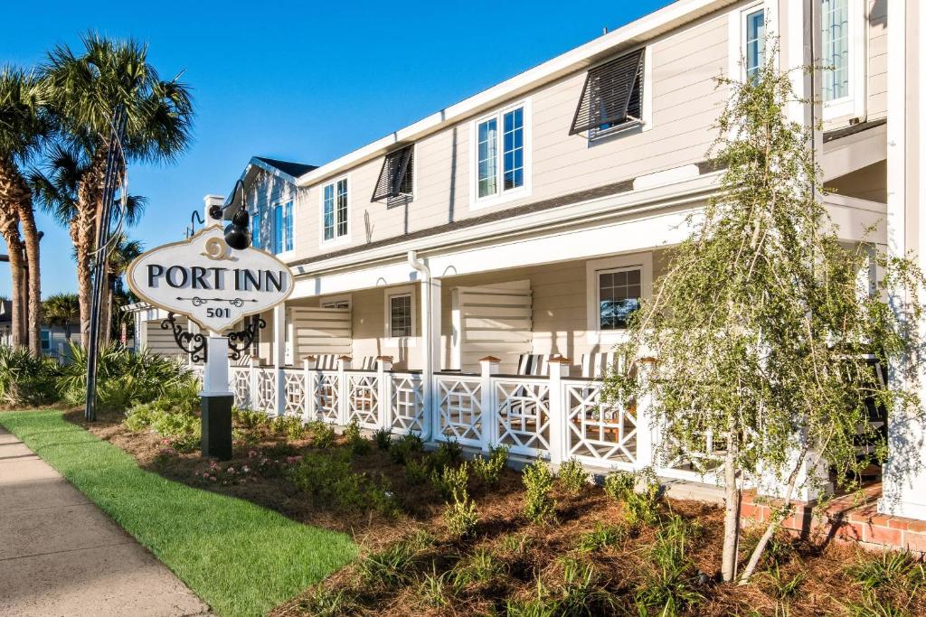 a sign in front of a white building with a port inn at The Port Inn - Port St Joe, an Ascend Collection Hotel in Port Saint Joe