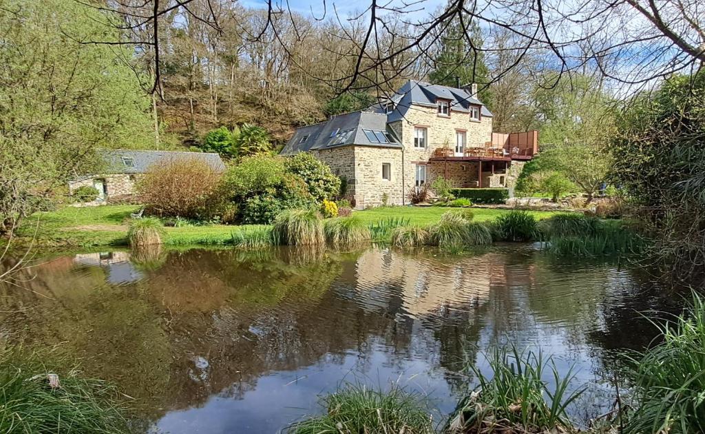 an old house with a pond in front of it at Moulin de Kervegan in Plouzélambre