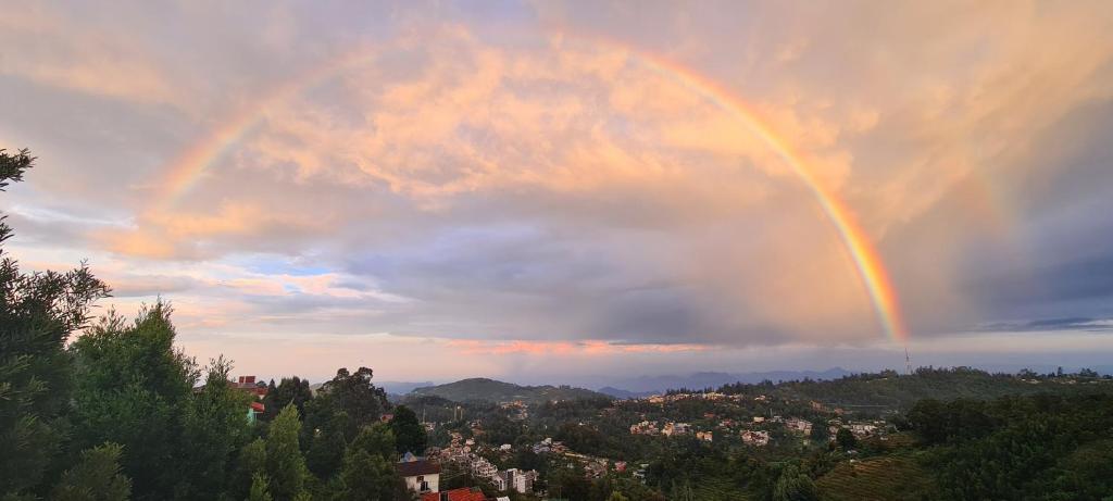 a rainbow in the sky over a city at Cloudwalks Homestay in Kodaikānāl