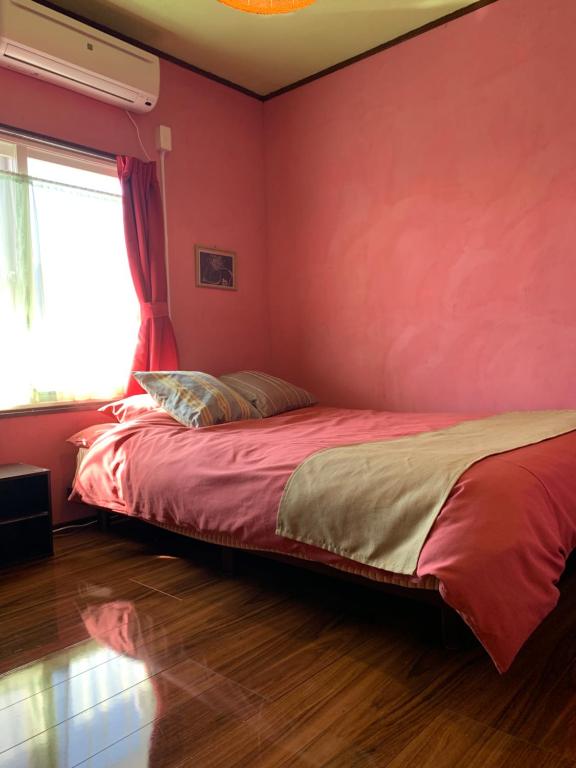 a bedroom with a bed with a red wall at Cozy Penguin House Bibai in Bibai